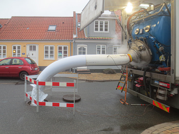 Lastbils ende hvorfra plastbeklædning kaldet strømper føres ned i kloak. 